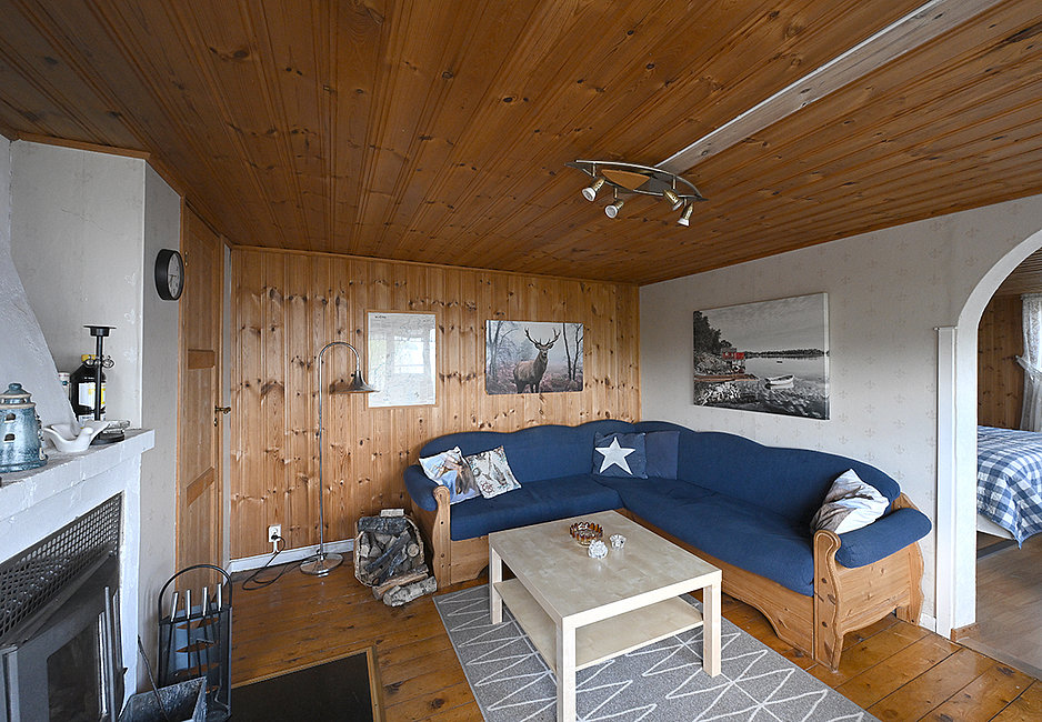 Gemütliches Wohnzimmer mit Sofa, Kaminofen und TV.
