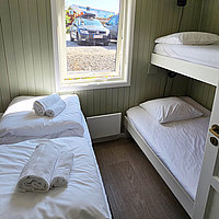 Schlazimmer mit Etagenbett plus Doppelbett in der Ferienwohnung Olufbua in der Hemmingodden Fishing Lodge in Ballstad auf den Lofoten.