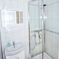 Das gekachelte Hauptbadezimmer mit Dusche und WC.