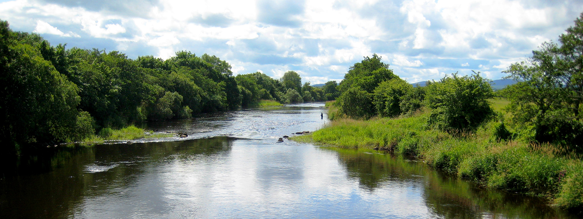 Ein Blick auf den River Moy, in dem entfernt ein Angler fischt.