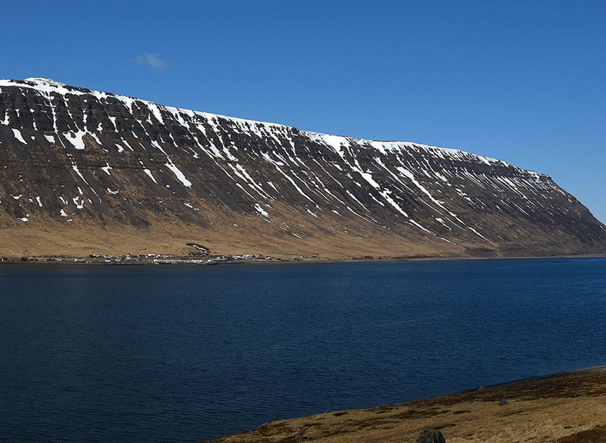Eine verschneite Landzuge zieht sich in die See von Súðavík.
