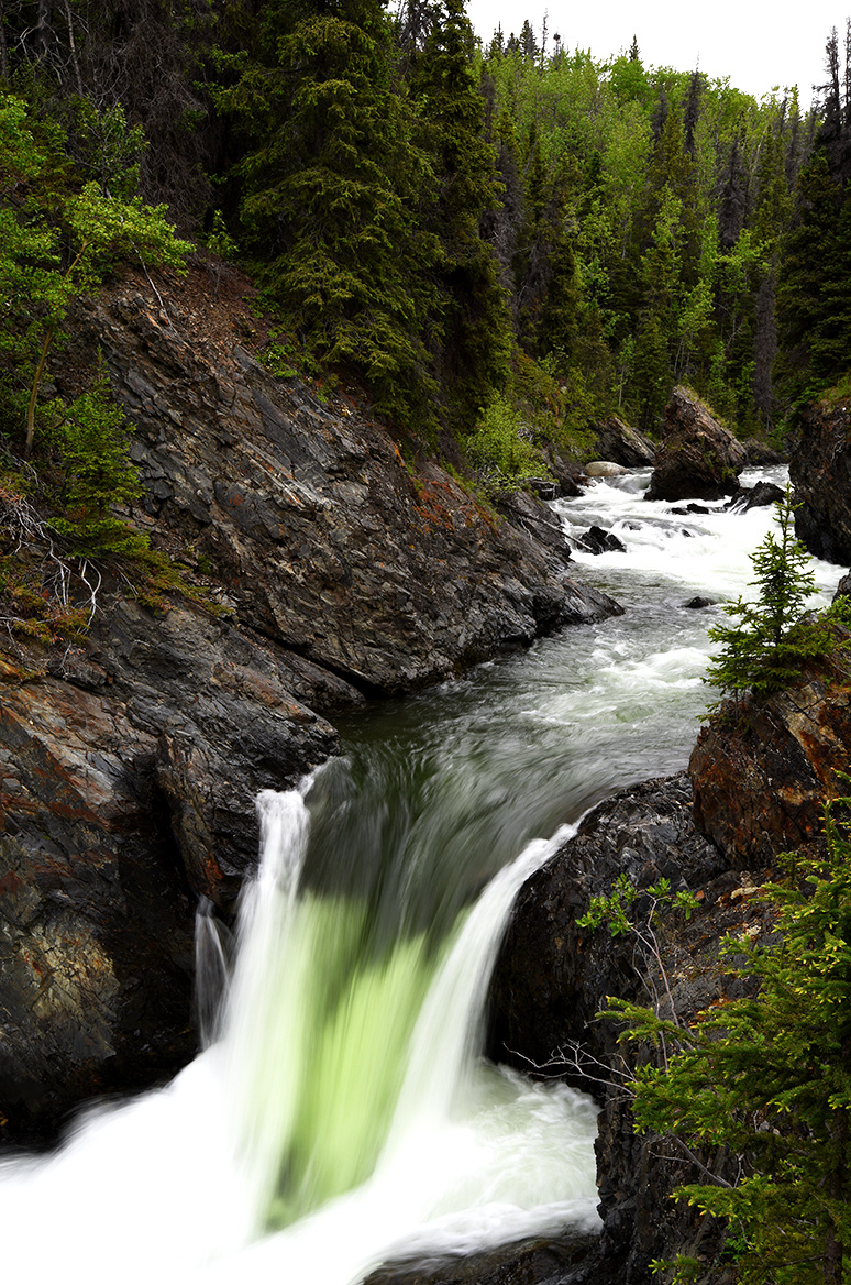 Ein kleiner Wasserfall in der bewaldeten Landschaft Kanadas.